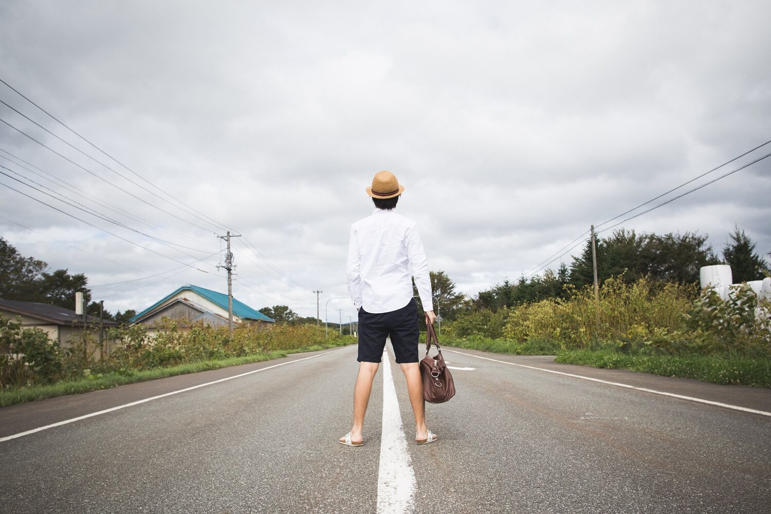 まっすぐな道路を歩く男性