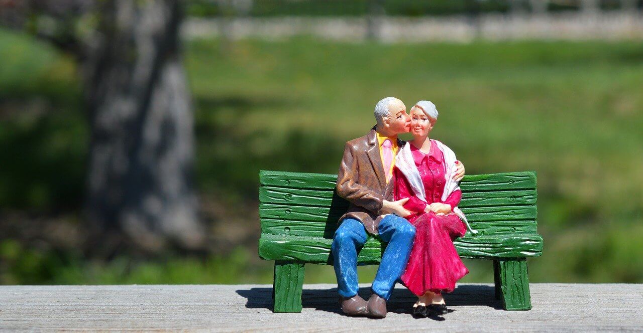 ベンチでキスする夫婦の画像